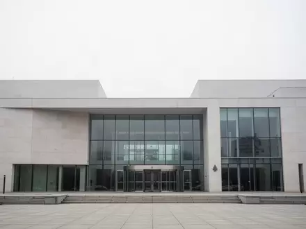 Modernes Verwaltungsgebäude mit minimalistischer Architektur und Glasfassade bei bewölktem Himmel. - Foto: über boerse-global.de