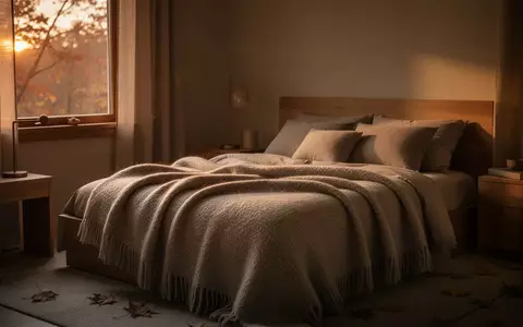 Ein minimalistisch eingerichtetes Schlafzimmer mit warmen Textilien und herbstlichem Licht, das eine ruhige Atmosphäre ausstrahlt. - Foto: über boerse-global.de