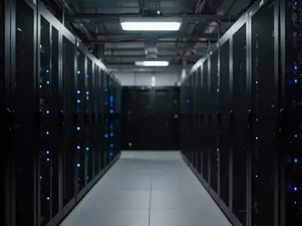 Dunkler Serverraum mit unkenntlichen Rack-Schränken und blauen Statusleuchten. - Foto: über boerse-global.de