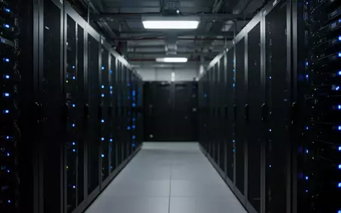 Dunkler Serverraum mit unkenntlichen Rack-Schränken und blauen Statusleuchten. - Foto: über boerse-global.de