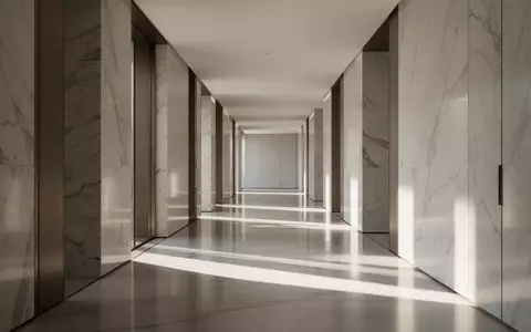 Ein minimalistischer, heller Flur mit poliertem Marmorboden und weichem Lichteinfall, der eine ruhige, sachliche Atmosphäre erzeugt. - Foto: über boerse-global.de