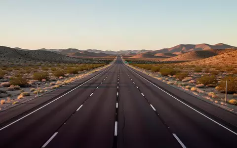 Eine leere, asphaltierte Fernstraße in einer weiten Wüstenlandschaft bei Sonnenuntergang. - Foto: über boerse-global.de