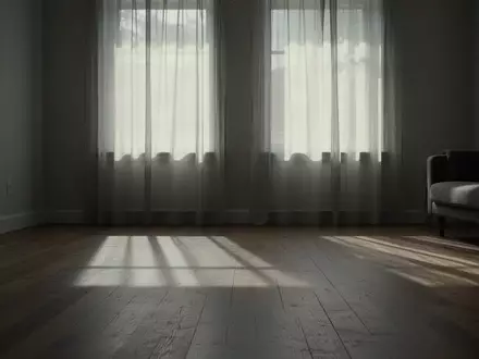 Ein minimalistisch eingerichteter, ruhiger Wohnraum mit sanftem Tageslichteinfall und langen Schatten auf einem Holzboden. - Foto: über boerse-global.de