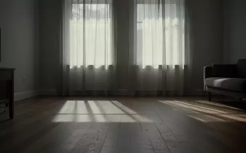 Ein minimalistisch eingerichteter, ruhiger Wohnraum mit sanftem Tageslichteinfall und langen Schatten auf einem Holzboden. - Foto: über boerse-global.de