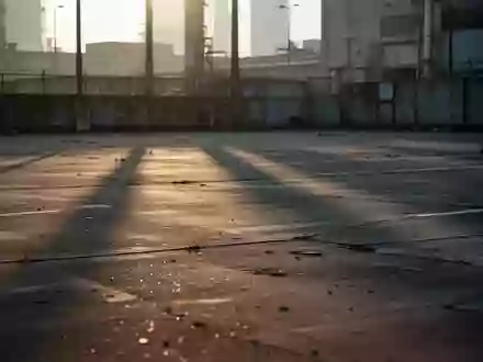 Ein verlassener, leerer Parkplatz bei Tagesanbruch mit langen Schatten auf dem Betonboden vor einer industriellen Kulisse. - Foto: über boerse-global.de