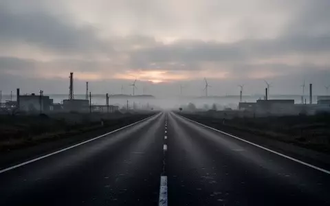 Eine leere Autobahn in der Dämmerung, die sich in einer nebligen Industrielandschaft verliert. - Foto: über boerse-global.de