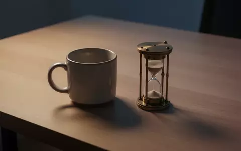 Eine leere Kaffeetasse und eine Sanduhr auf einem hölzernen Schreibtisch bei Dämmerungslicht. - Foto: über boerse-global.de
