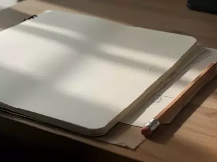 Ein offenes Notizbuch mit einem Bleistift auf einem Holztisch in sanftem Tageslicht. - Foto: über boerse-global.de