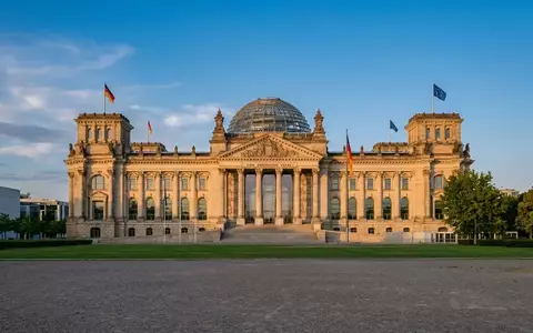 Das Berliner Reichstagsgebäude bei goldenem Sonnenlicht vor einem klaren Himmel. - Foto: über boerse-global.de