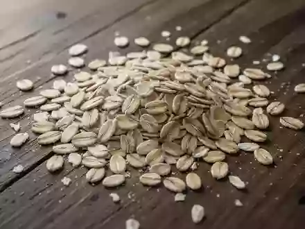 Nahaufnahme von rohen Haferflocken, die auf einem dunklen Holztisch verstreut liegen. - Foto: über boerse-global.de