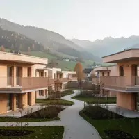 Moderne Wohnhausanlage in einer ländlichen Umgebung mit begrünten Außenanlagen und architektonisch schlichten Fassaden. - Foto: über boerse-global.de