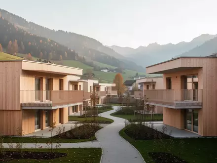 Moderne Wohnhausanlage in einer ländlichen Umgebung mit begrünten Außenanlagen und architektonisch schlichten Fassaden. - Foto: über boerse-global.de