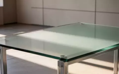 Ein minimalistischer, leerer Arbeitsplatz mit einem Glastisch und weichem, natürlichem Licht in einer ruhigen Umgebung. - Foto: über boerse-global.de