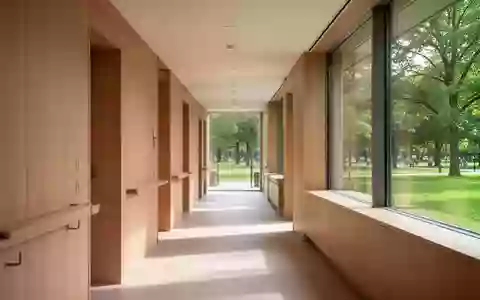 Ein heller, minimalistischer Flur in einer modernen Kureinrichtung mit Holzelementen und Blick in einen Park. - Foto: über boerse-global.de