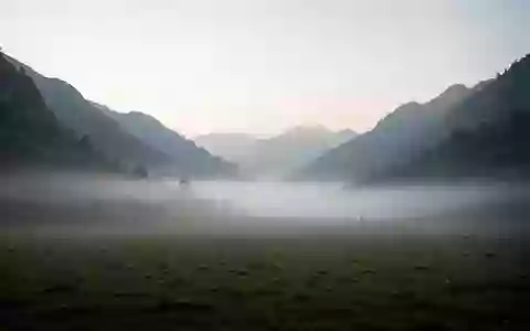 Eine neblige, stille Gebirgslandschaft in der Morgendämmerung, die Ruhe und Abgeschiedenheit symbolisiert. - Foto: über boerse-global.de