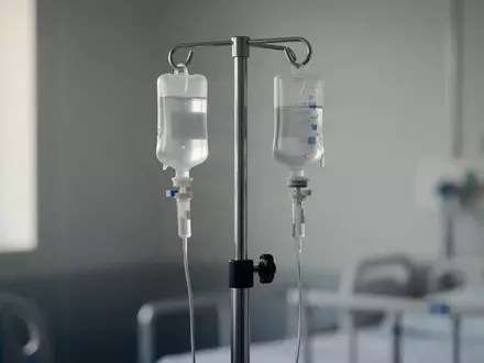 Ein steriler, leerer Infusionsständer in einem minimalistisch eingerichteten Krankenhauszimmer bei natürlichem Lichteinfall. - Foto: über boerse-global.de