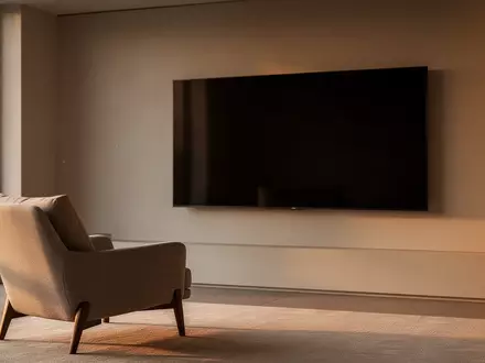 Modernes, minimalistisches Wohnzimmer mit einem leeren, dunklen Fernsehbildschirm an einer schlichten Wand bei Tageslicht. - Foto: über boerse-global.de