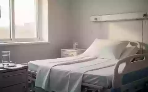 Ein klinisch-steriles Krankenzimmer mit einem ordentlich gemachten Bett und einem Glas Wasser in ruhigem, natürlichem Licht. - Foto: über boerse-global.de