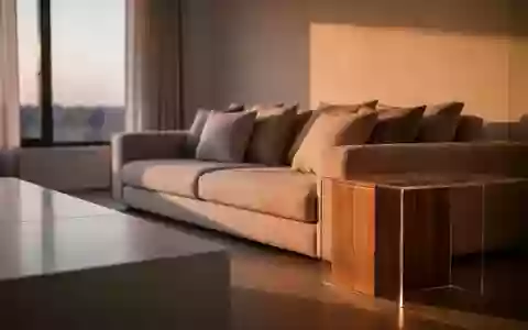 Ein aufgeräumtes, minimalistisches Wohnzimmer im warmen Licht des Abends mit einer ordentlichen Couch und leeren Oberflächen. - Foto: über boerse-global.de