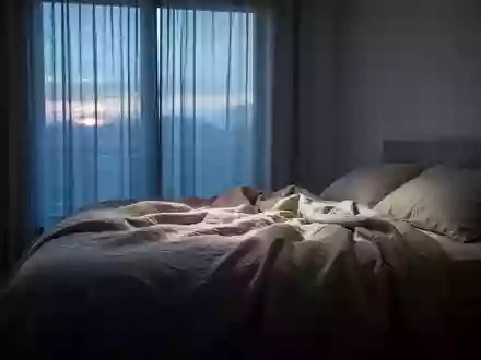 Ein ungemachtes Bett in einem spärlich beleuchteten Schlafzimmer während der Morgendämmerung. - Foto: über boerse-global.de