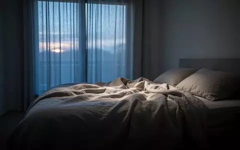 Ein ungemachtes Bett in einem spärlich beleuchteten Schlafzimmer während der Morgendämmerung. - Foto: über boerse-global.de