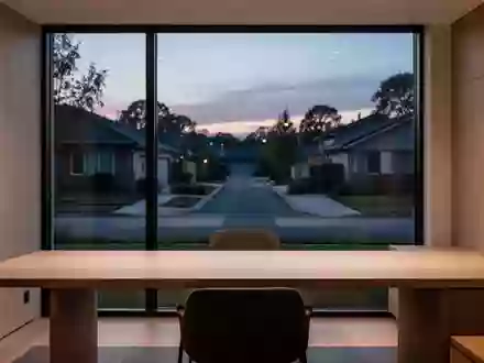 Ein minimalistisches Heimbüro mit einem leeren Schreibtisch vor einem Fenster bei Dämmerung. - Foto: über boerse-global.de