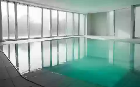 Ein leeres, helles Hallenbad mit ruhigem, blauem Wasser und natürlichem Lichteinfall. - Foto: über boerse-global.de