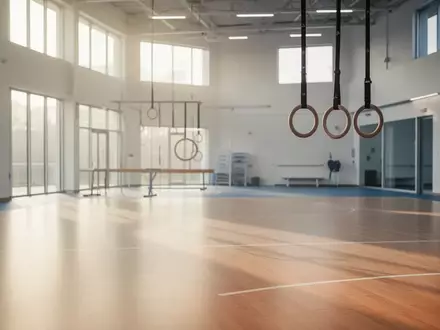 Eine helle, moderne Sportstätte mit poliertem Holzboden und Turnringen in einer ruhigen, klinischen Umgebung. - Foto: über boerse-global.de