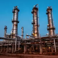 Ein weitläufiges industrielles Raffineriegelände mit hohen Destillationskolonnen und Rohrleitungen bei Dämmerung. - Foto: über boerse-global.de