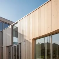Helle, moderne Architektur einer Kindertagesstätte mit Holzfassade und großen Glasfronten bei natürlichem Tageslicht. - Foto: über boerse-global.de