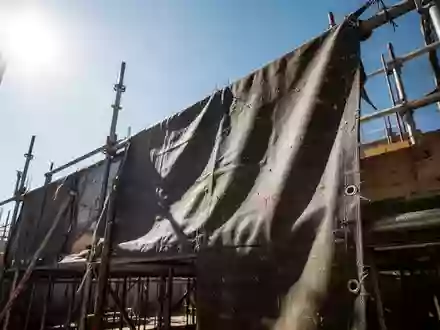 Nahaufnahme von robustem, dunklem Arbeitsstoff auf einer Baustelle bei intensivem Sonnenlicht zur Veranschaulichung des UV-Schutzes. - Foto: über boerse-global.de
