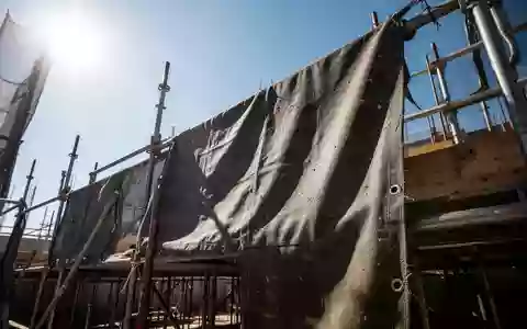 Nahaufnahme von robustem, dunklem Arbeitsstoff auf einer Baustelle bei intensivem Sonnenlicht zur Veranschaulichung des UV-Schutzes. - Foto: über boerse-global.de