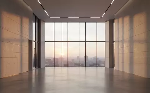 Ein minimalistisches, leeres Büro-Foyer mit klaren Linien und natürlichem Licht, das durch bodentiefe Fenster fällt. - Foto: über boerse-global.de