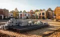 Eine Baustelle mit aufgestapelten Baumaterialien und Rohbauten in einem Wohngebiet an einem sonnigen Herbsttag. - Foto: über boerse-global.de
