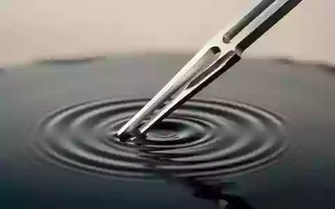 Eine Stimmgabel erzeugt konzentrische Wellen auf einer ruhigen Wasseroberfläche. - Foto: über boerse-global.de