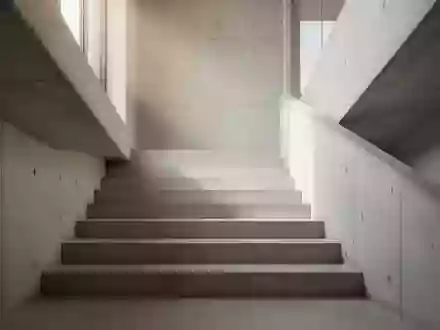 Eine minimalistische Betontreppe in einem hellen Gebäude, die nach oben führt, bei natürlichem Lichteinfall. - Foto: über boerse-global.de