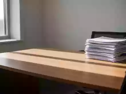 Ein aufgeräumter Schreibtisch mit einem Stapel Akten in einem hellen, sonnendurchfluteten Büro. - Foto: über boerse-global.de