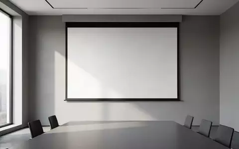 Ein minimalistischer, leerer Konferenzraum mit einer unbeschriebenen Projektionsfläche vor einer grauen Wand. - Foto: über boerse-global.de