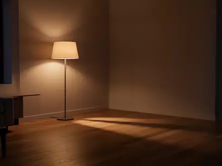 Ein minimalistisch eingerichtetes, ruhig wirkendes Wohnzimmer am Abend mit warmem Licht und Schattenwurf auf einem Holzboden. - Foto: über boerse-global.de