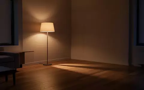 Ein minimalistisch eingerichtetes, ruhig wirkendes Wohnzimmer am Abend mit warmem Licht und Schattenwurf auf einem Holzboden. - Foto: ĂŒber boerse-global.de