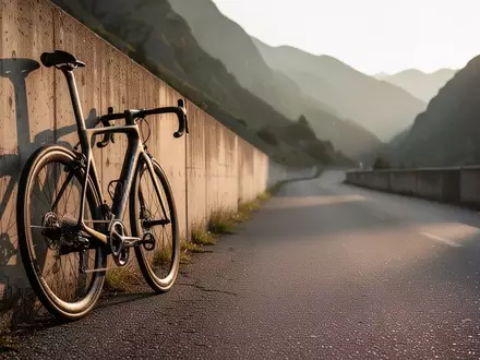 Ein Rennrad aus Carbon lehnt an einer Betonmauer auf einer sonnigen Bergstraße. - Foto: über boerse-global.de