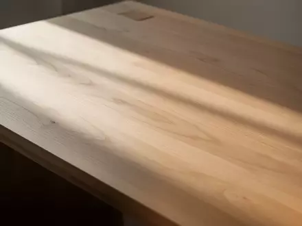Ein minimalistischer, leerer Schreibtisch aus Holz in hellem, natürlichem Tageslicht mit weichen Schatten. - Foto: über boerse-global.de