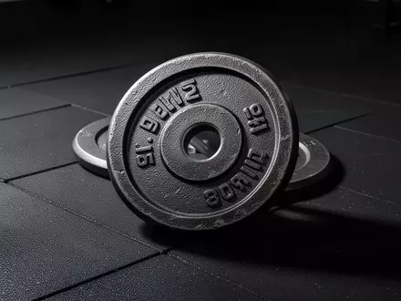Eine schwere Hantelscheibe aus Metall auf einem dunklen Gummiboden in einem Fitnessstudio. - Foto: über boerse-global.de