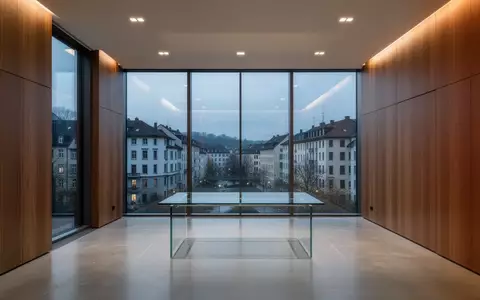 Ein minimalistisch eingerichteter, moderner Büroraum mit großen Glasfronten und schlichter Architektur in der Abenddämmerung. - Foto: über boerse-global.de