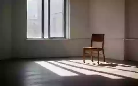 Ein minimalistischer, sonnendurchfluteter Raum mit einem leeren Holzstuhl und weichen Schatten auf dem Boden. - Foto: über boerse-global.de