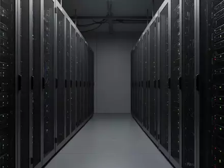 Reihen von metallischen Server-Schränken in einem schlichten, industriellen Rechenzentrum bei gedimmtem Licht. - Foto: über boerse-global.de