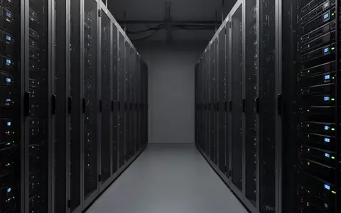 Reihen von metallischen Server-Schränken in einem schlichten, industriellen Rechenzentrum bei gedimmtem Licht. - Foto: über boerse-global.de