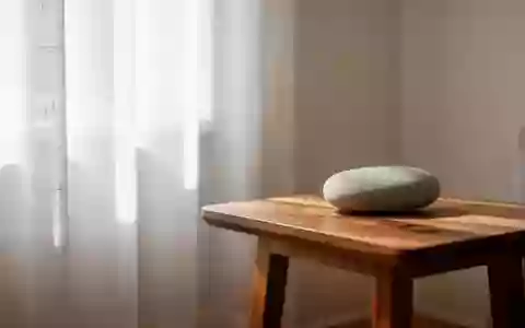 Ein minimalistischer Raum mit weichem Tageslicht und einem einzelnen glatten Stein auf einem Holztisch. - Foto: über boerse-global.de
