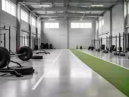 Große, leere Trainingshalle mit Kunstrasenbahn und funktionellem Fitnessequipment in einer modernen Industriehalle. - Foto: über boerse-global.de