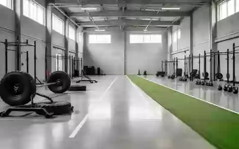 Große, leere Trainingshalle mit Kunstrasenbahn und funktionellem Fitnessequipment in einer modernen Industriehalle. - Foto: über boerse-global.de